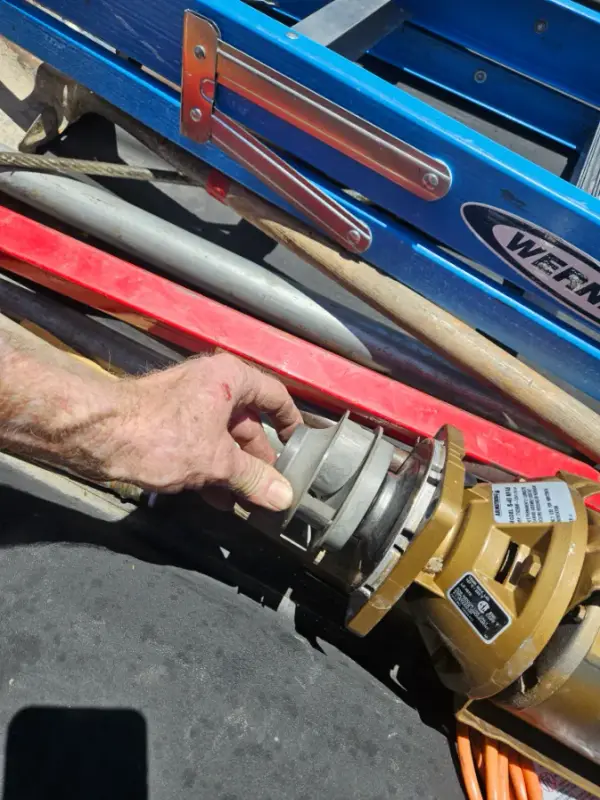 Plumber holding the check assembly pulled from a brass backflow preventer on the truck bed
