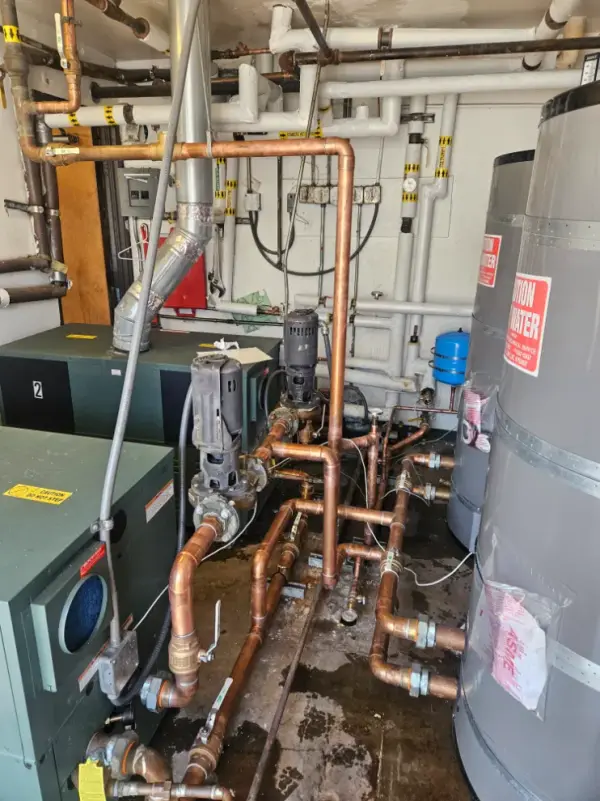 Commercial boiler room with copper piping, circulating pumps, an expansion tank and storage water heaters