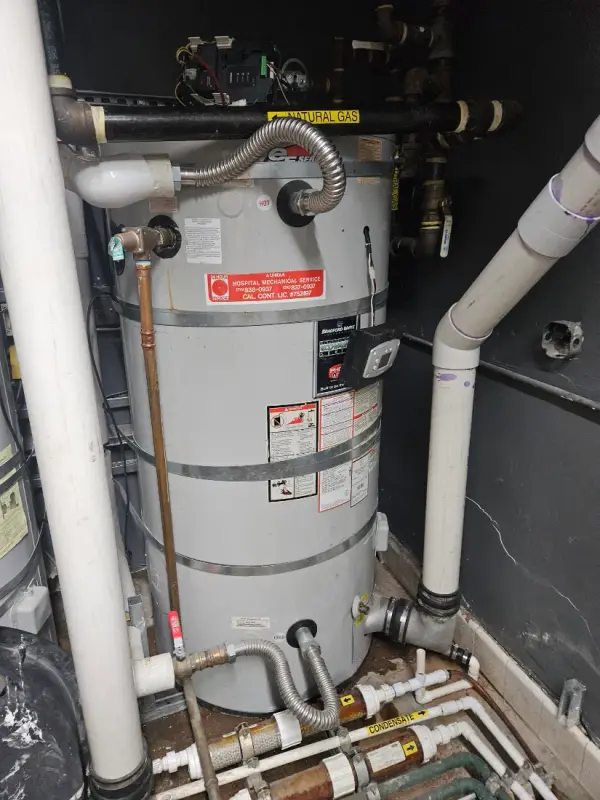 Commercial gas water heater with flexible connectors, PVC venting and a labeled natural gas line