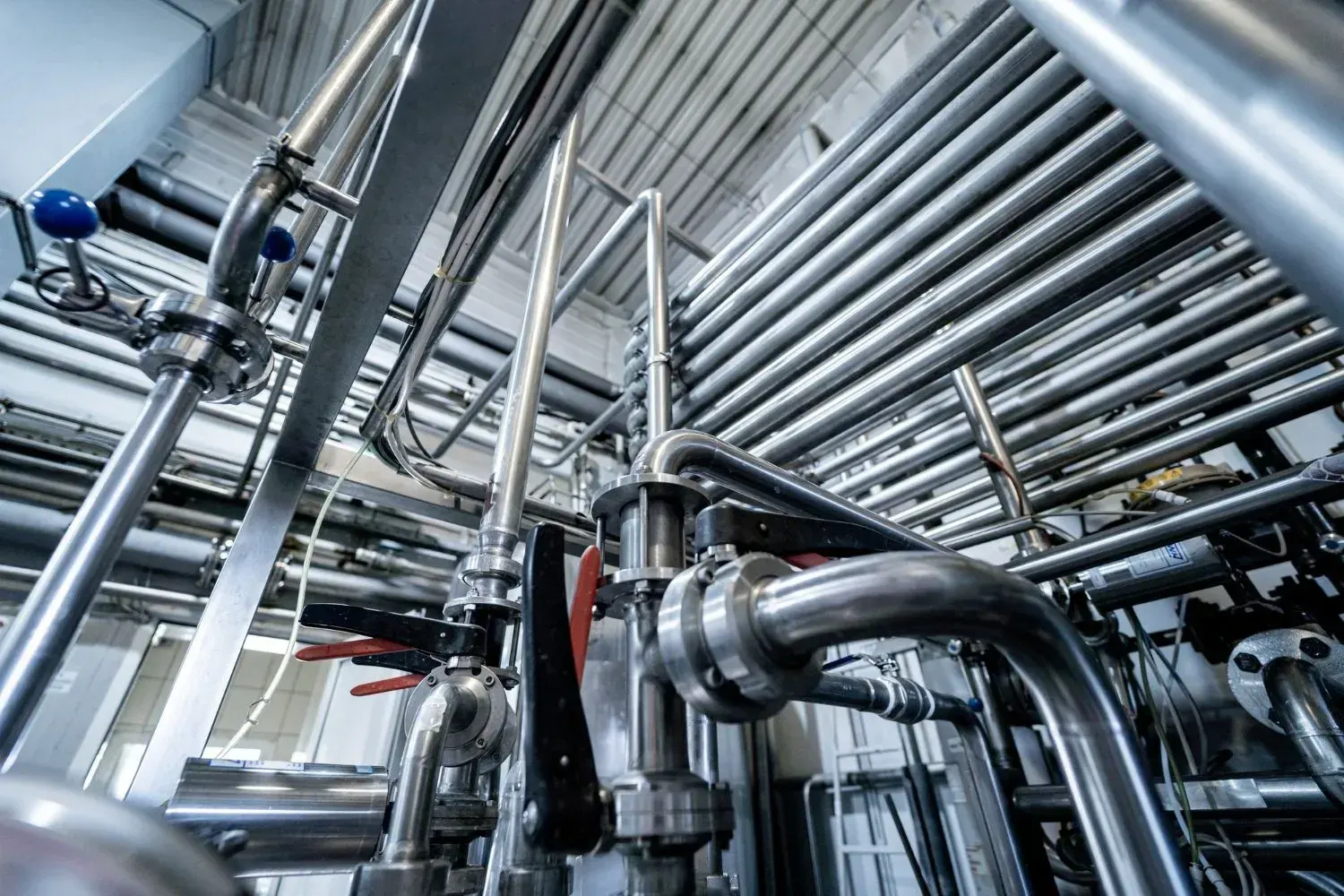 Low-angle view of stainless steel pipes, clamps and butterfly valves in an industrial facility