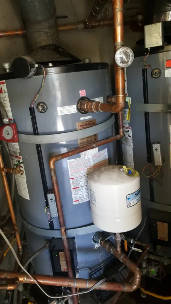 Commercial water heater in a mechanical room with copper supply piping, a thermal expansion tank and a temperature gauge