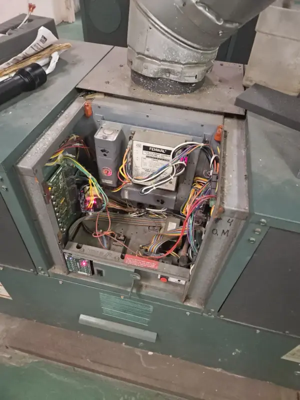Commercial water heater with its front panel removed, showing the ignition control module and wiring