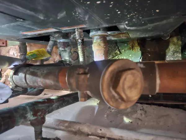 Corroded copper and galvanized supply lines beneath a commercial dish machine
