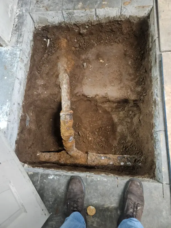Corroded galvanized water line uncovered in a slab excavation inside a building