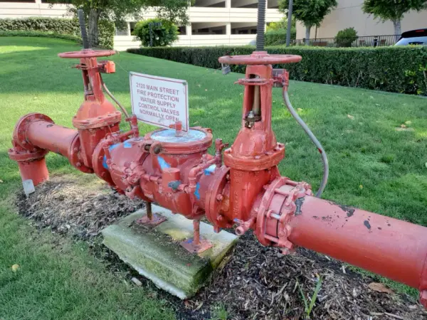 Red backflow prevention assembly on a commercial fire-protection water supply in a landscaped lawn
