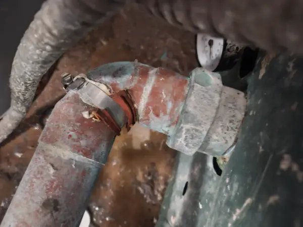 Leaking galvanized elbow and union under a commercial sink, patched with a clamp