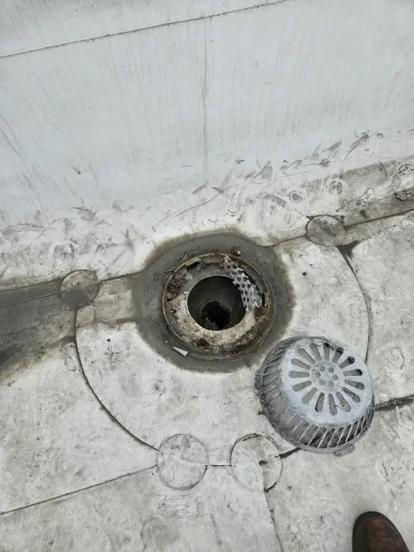 Open roof drain bowl with the strainer dome removed, showing the cleared outlet