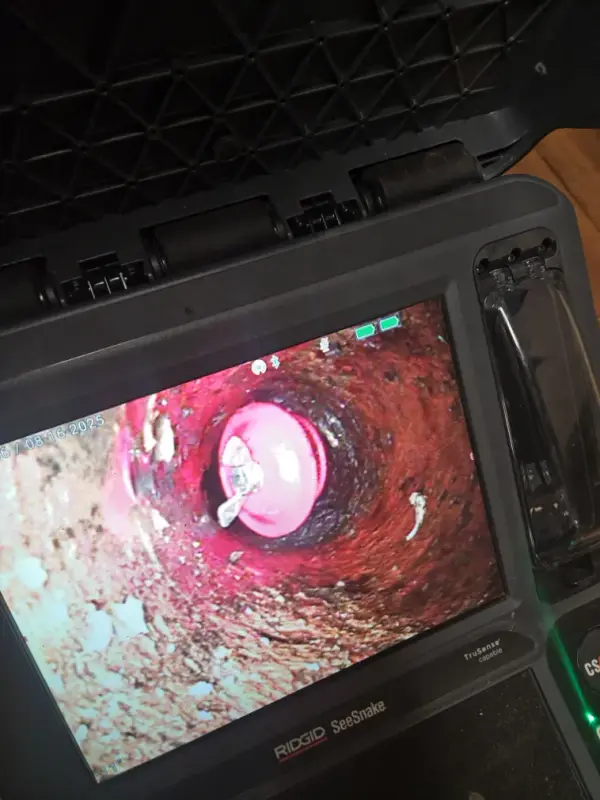 RIDGID SeeSnake camera monitor showing the inside of a drain pipe during a sewer inspection