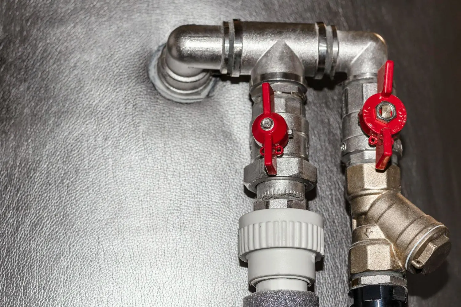 Chrome pipe fittings with red-handled ball shutoff valves and a brass Y-strainer