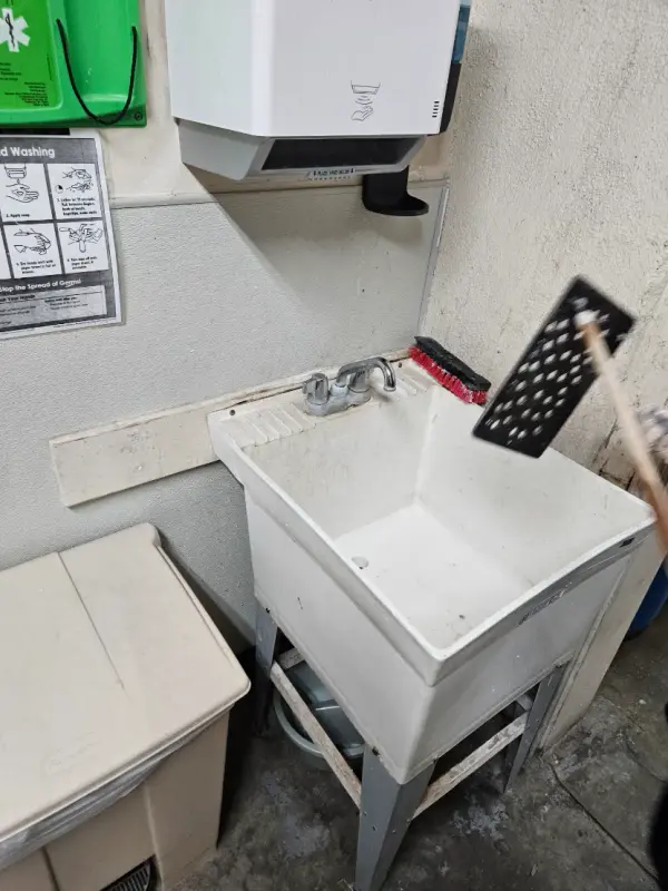 Utility mop sink with a two-handle faucet in a janitor’s closet