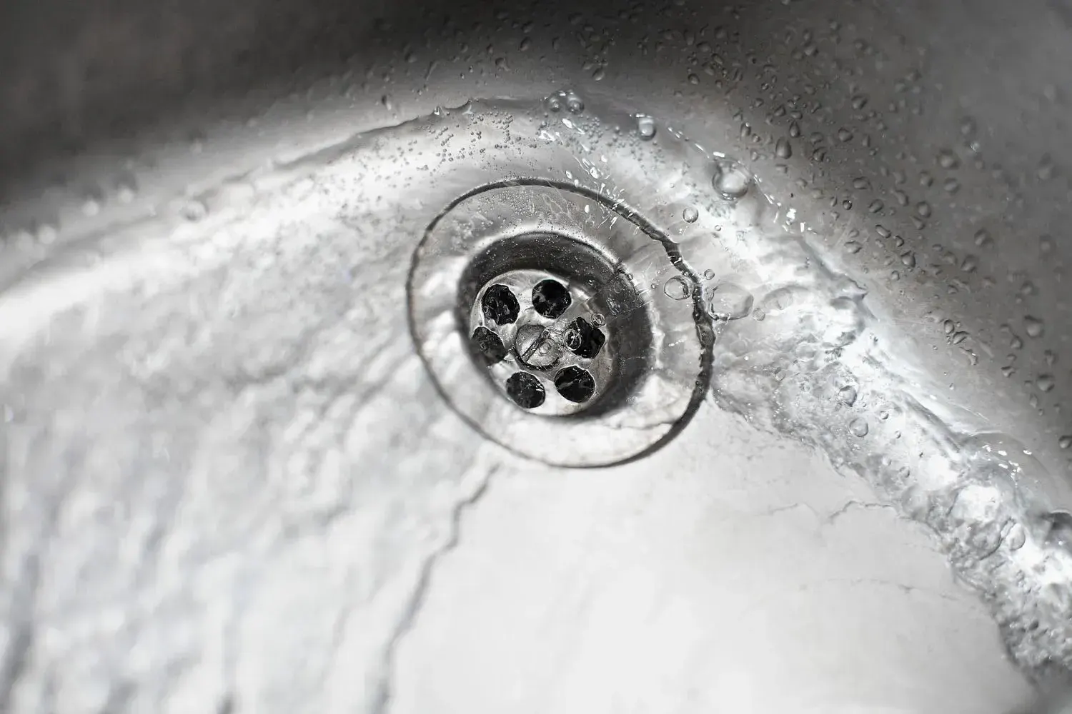 Water swirling down a stainless steel sink drain