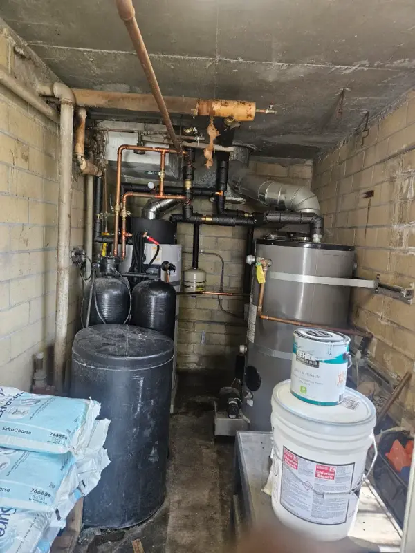 Mechanical room holding water softener tanks, a commercial water heater and copper distribution piping