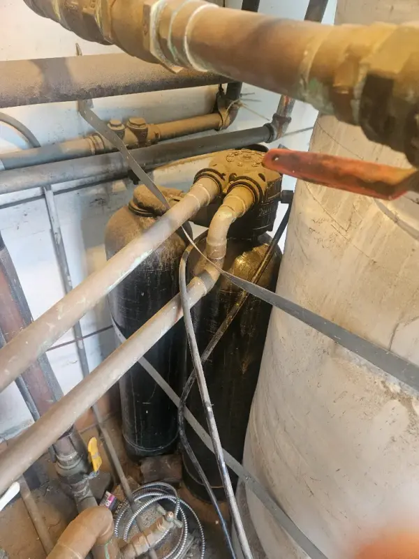 Water softener tanks and brass control valve piped into a commercial water heater